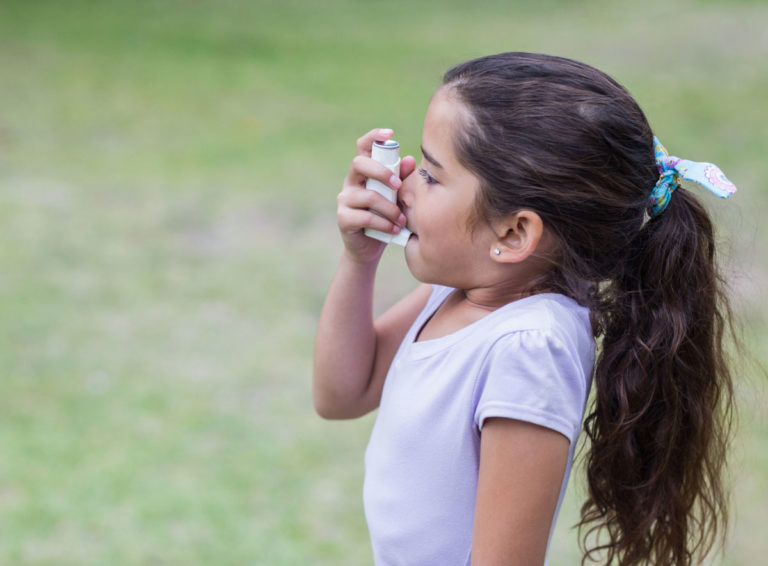 Young girl using an asthma inhaler