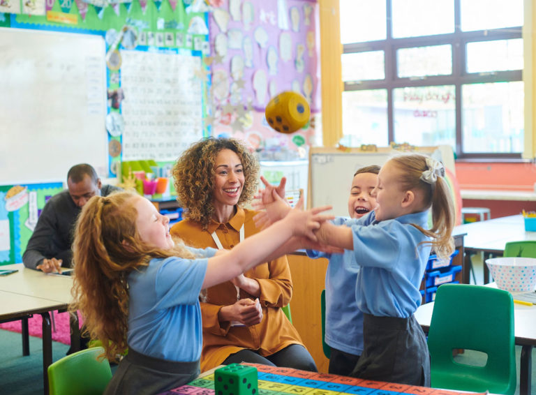 Teacher watching and engaging with kids throwing a toy