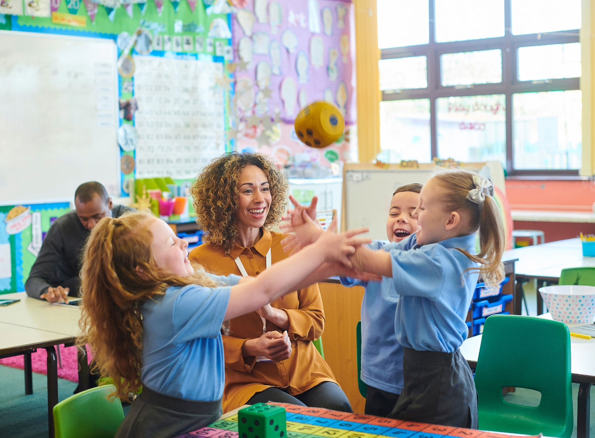 Teacher watching and engaging with kids throwing a toy