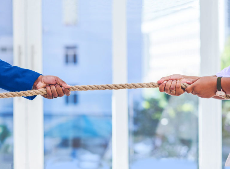 Two people showing conflict by pulling rope in tug-of-war