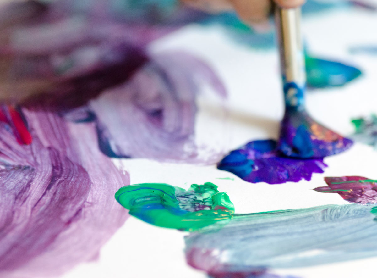 Paint splotches on a canvas with a paint brush creatively mixing colors