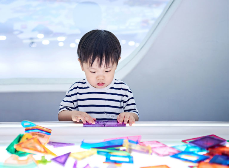 Small boy improves brain development while concentrating on puzzle shapes