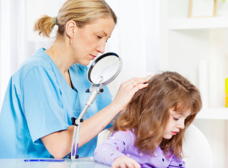 Nurse looks through child's hair with magnifying glass for lice