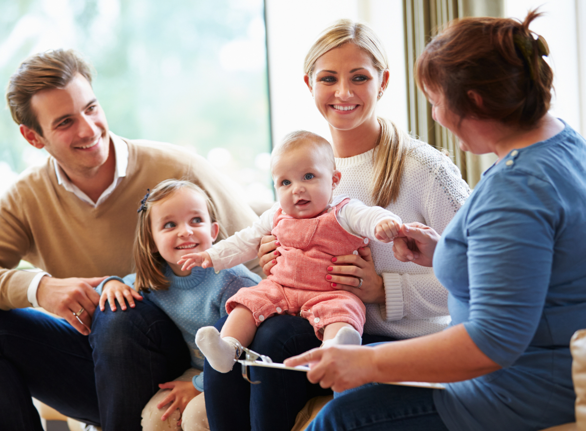 Parents with young children on their laps engage with child care center teacher