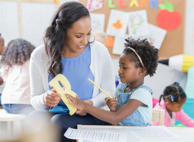 Teacher shows a capital letter B to a young girl for early childhood education