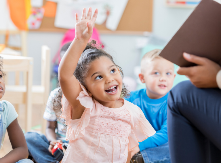 Girl in child care center class with hand raised