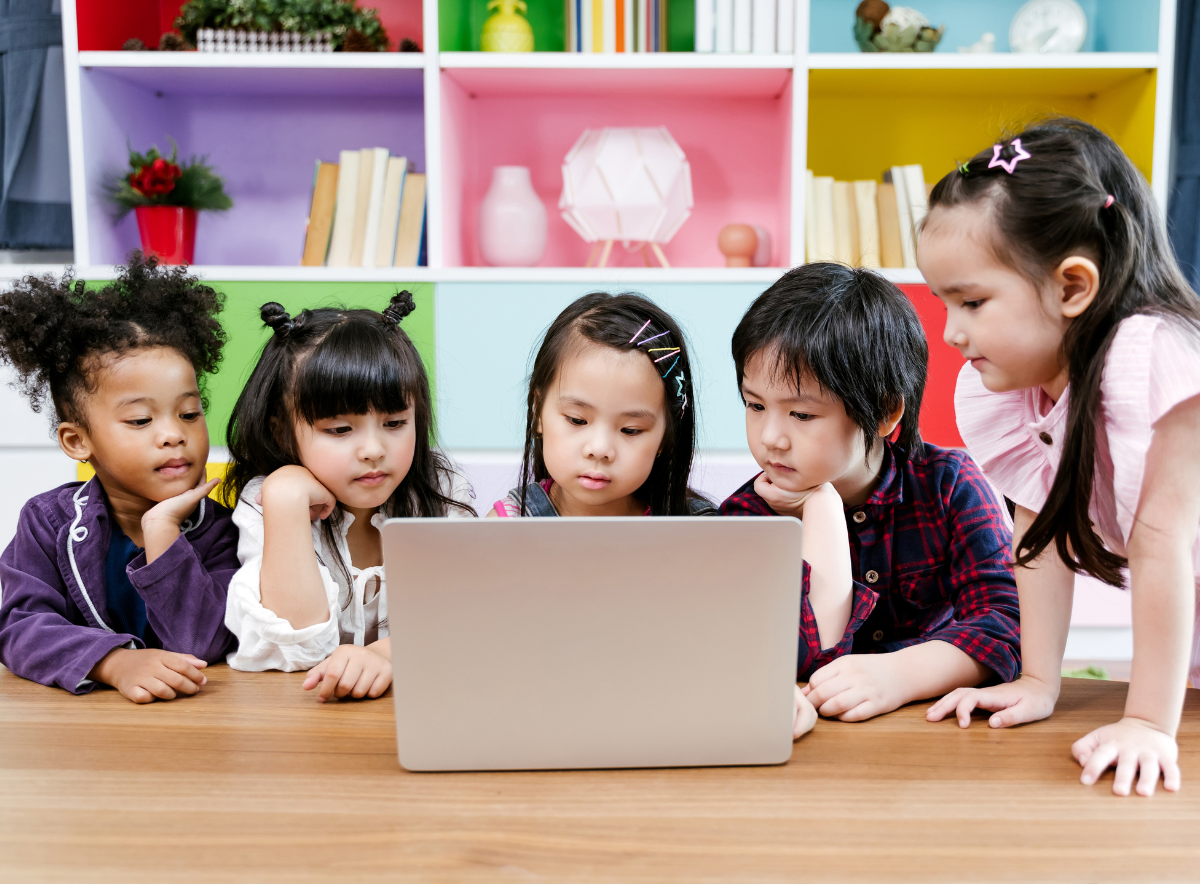 Child care center children concentrating and looking at a laptop