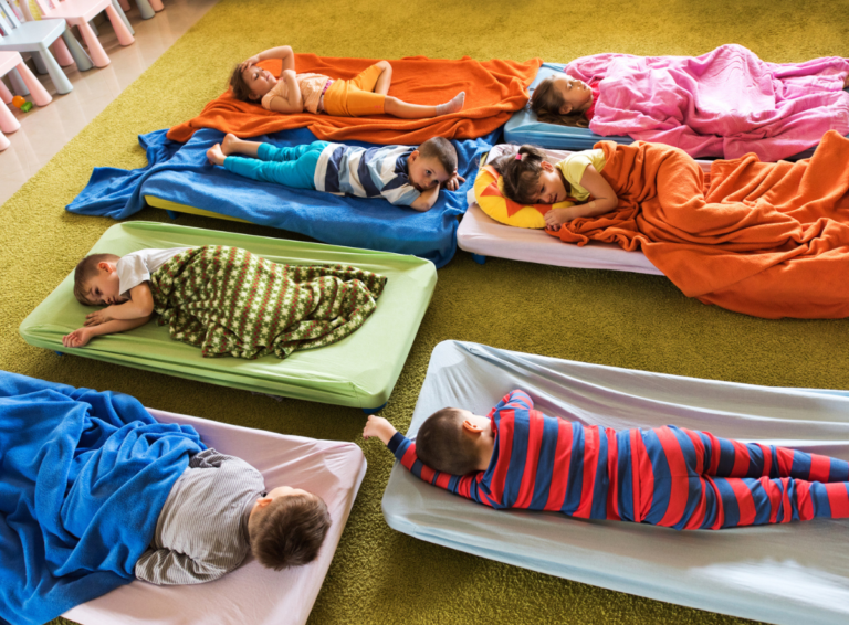 Young children laying on mats rest during nap time at a child care center