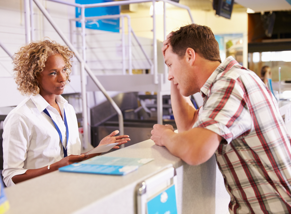 Woman at front desk helping upset, frustrated angry man