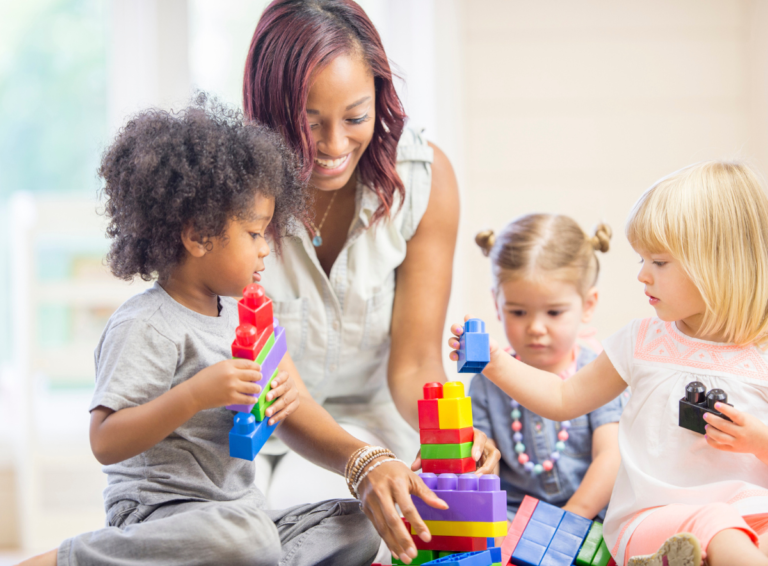 Teacher helping children stack blocks at child care center