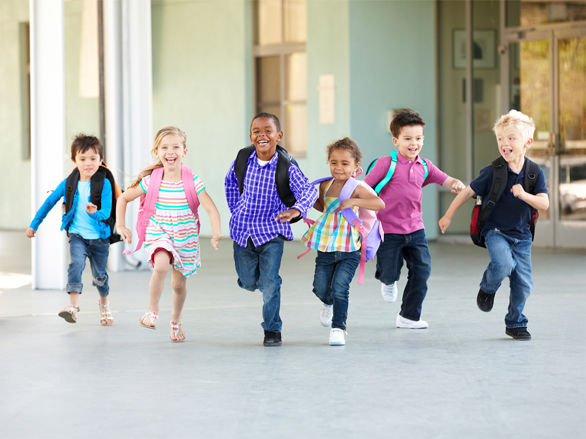Smiling children running wearing backpacks
