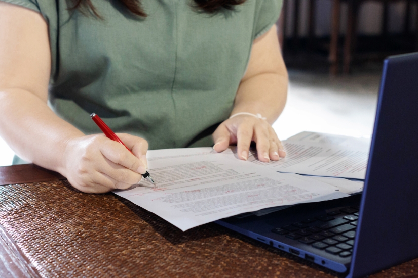 A woman makes edits to a piece of paper.