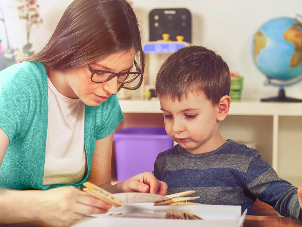 A teacher helps a student make a craft.