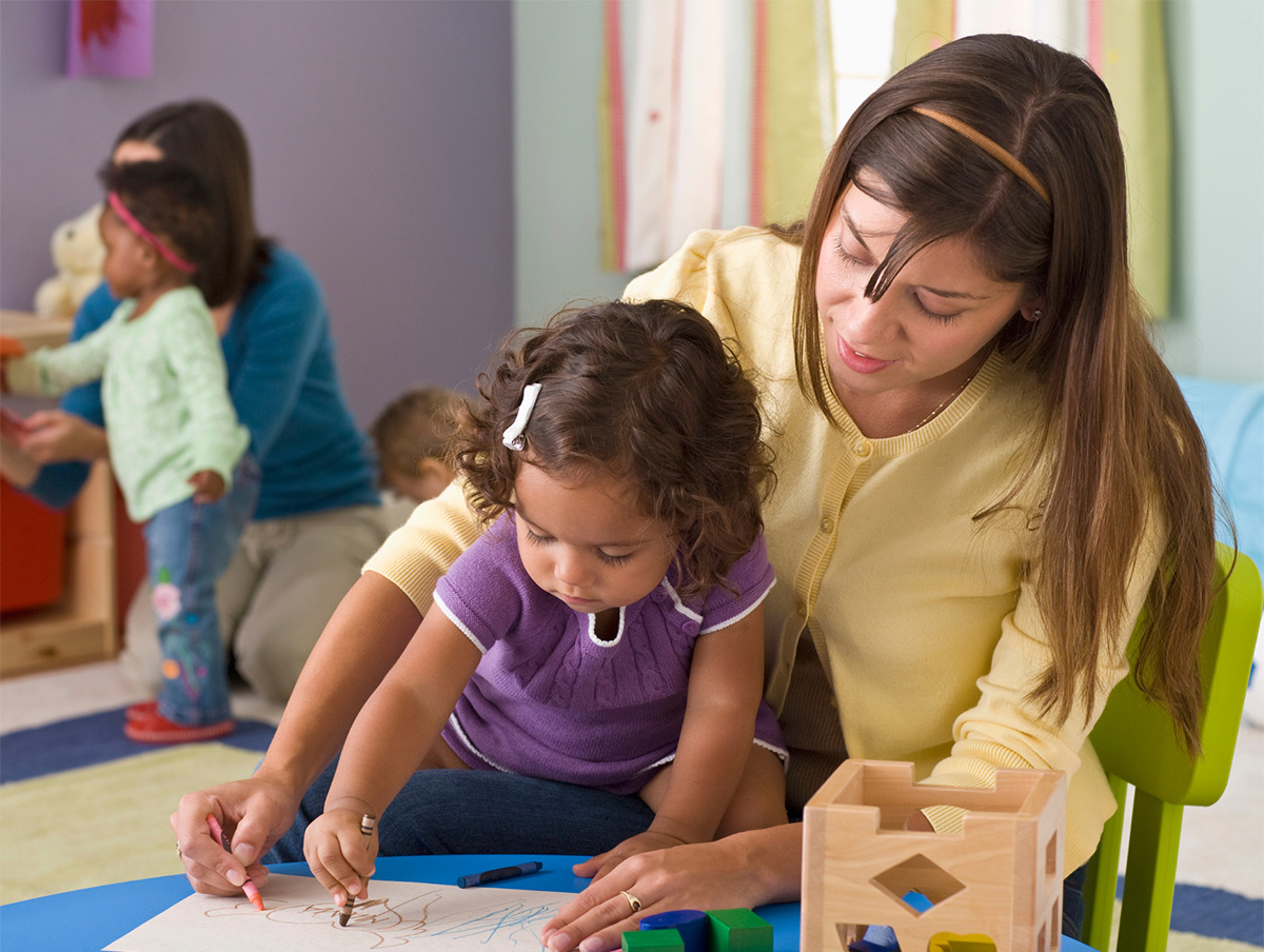 teacher and preschooler drawing with crayons