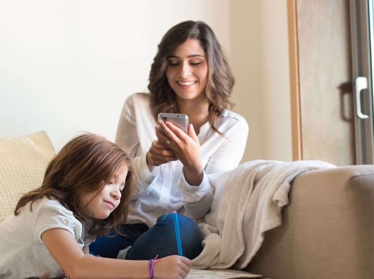 Young mother looking at phone with daughter.