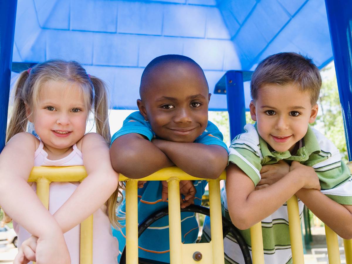 3 Children smile on a playground set