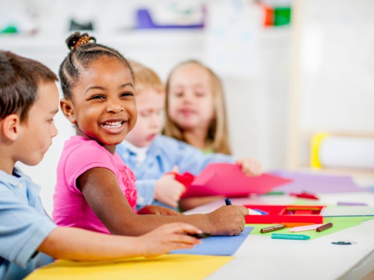 Children smiling while coloring at child card center