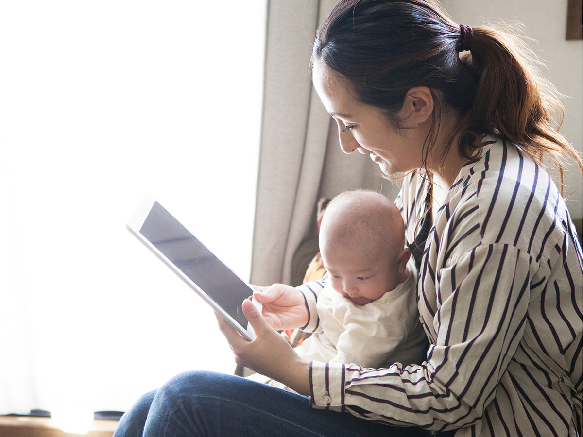 mother with infant on lap with a tablet