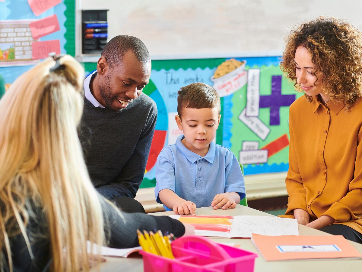 Parents sit down with their child and their child's teacher for a parent teacher conference.