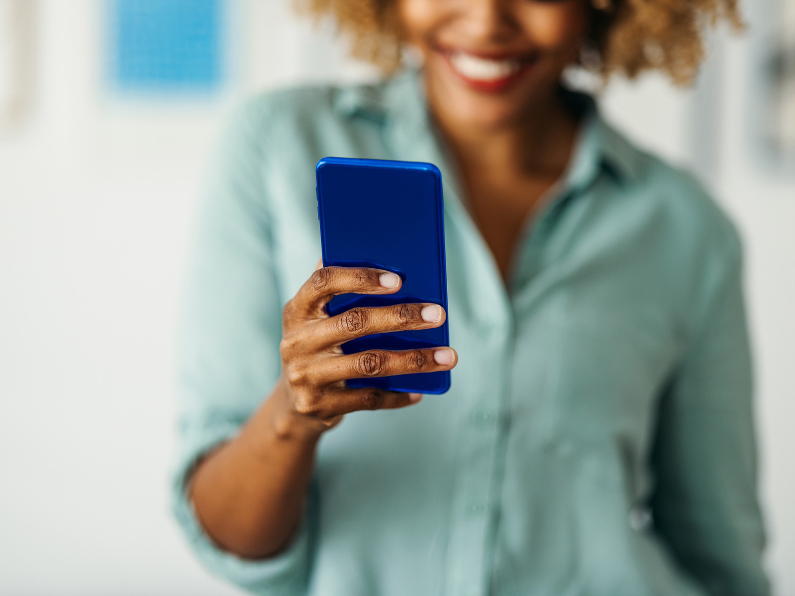 woman smiling holding blue phone