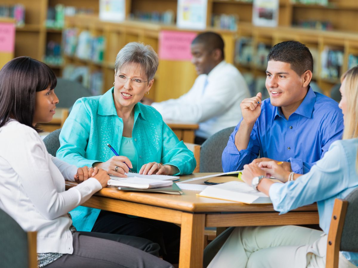 Teachers sit in a library and have a discussion